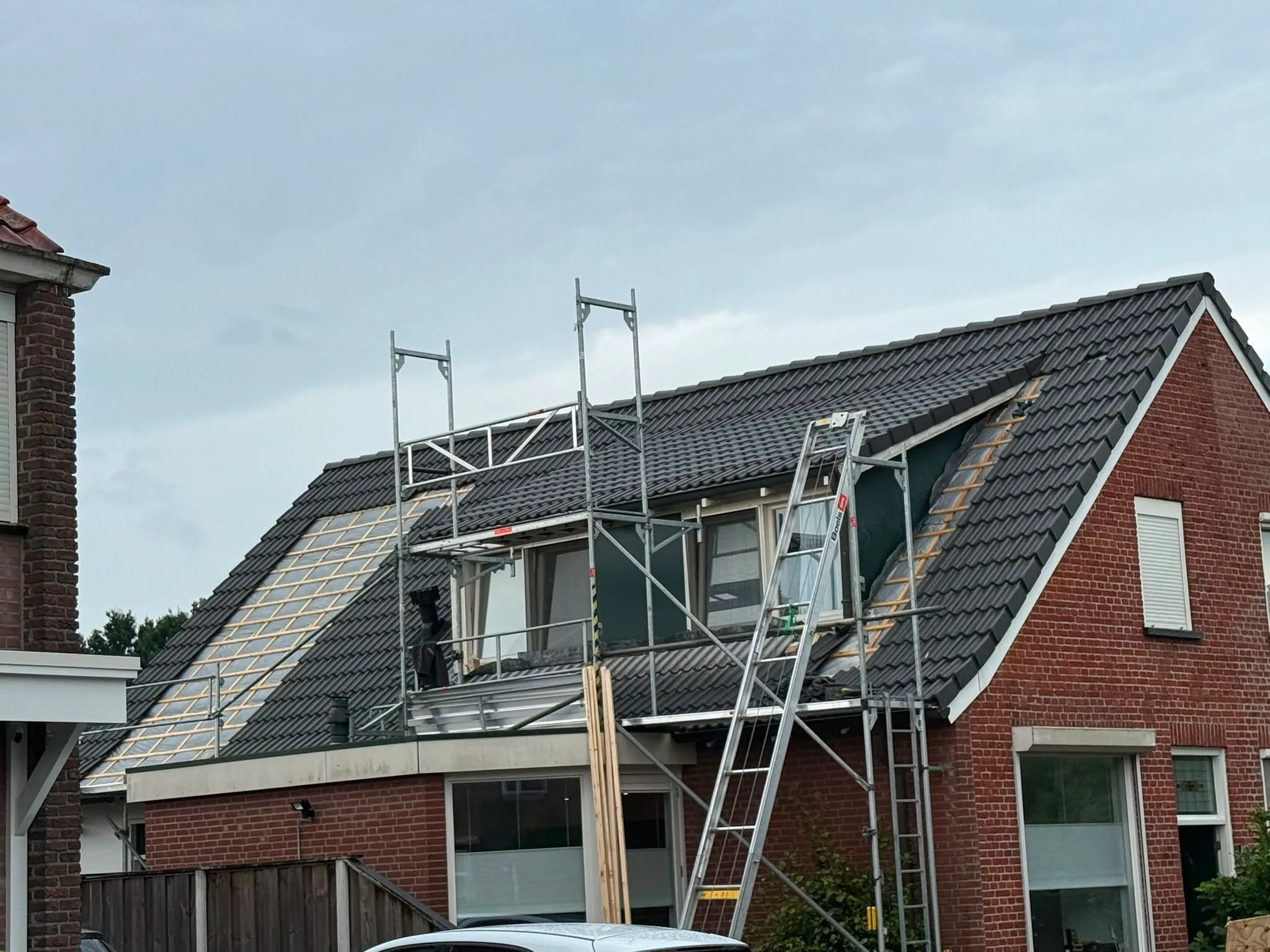 Dakrenovatie aan baksteenhuis met steiger